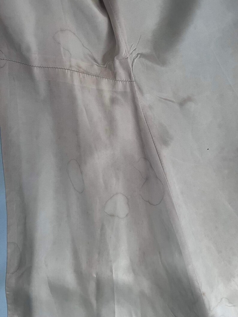 May include: A close-up of a light beige fabric with several brown stains.