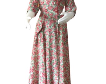 May include: A vintage floral print dress with a double-breasted bodice and a full skirt. The dress features a green and pink floral pattern, a collared neckline, and three-quarter sleeves. The dress is displayed on a mannequin.