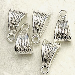 May include: Five silver-toned pendant bails with a textured, ridged design. Each bail has a round loop at the top and a slightly curved, open bottom.
