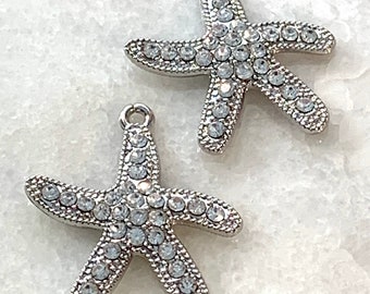 May include: Two silver starfish charms with clear rhinestones. The charms are perfect for jewelry making or adding a touch of sparkle to crafts.