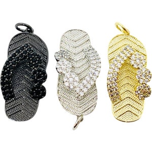 May include: Three flip-flop charms, one black, one silver with clear rhinestones, and one gold with clear rhinestones.