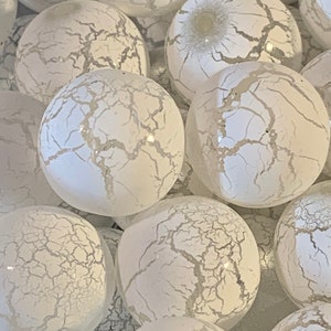 May include: A group of white glass ornaments with a crackled finish. The ornaments are round and have a subtle shimmer.