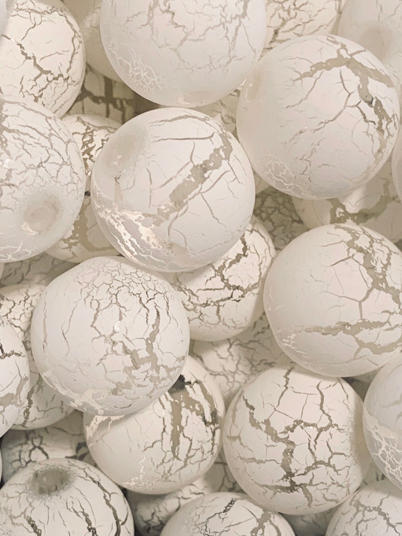 May include: A close-up of a group of white, textured, round ornaments. The ornaments have a crackled finish and are arranged in a pile.