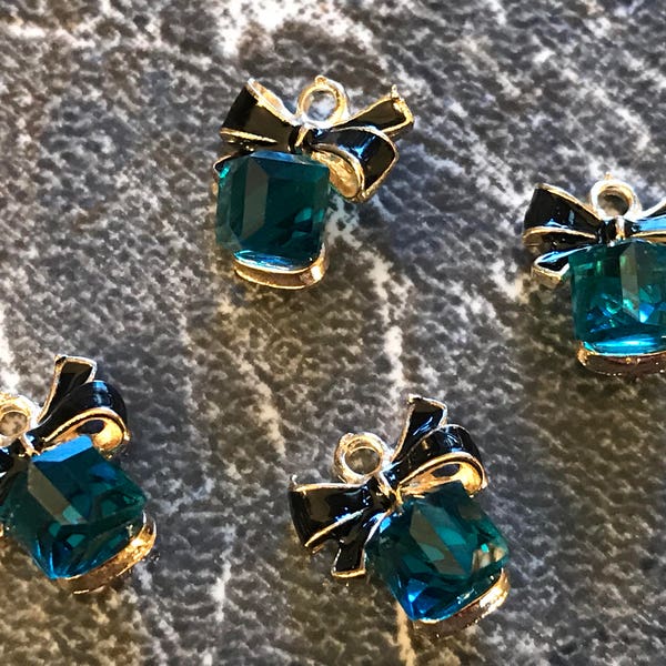 4 bluish green/teal colored crystal/rhinestone gold tone charms with black enamel bow charms - cube shaped - gift box