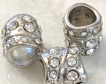 May include: Three silver-toned metal beads with clear rhinestone embellishments. The beads are designed to be used as spacers or charms on a bracelet or necklace.