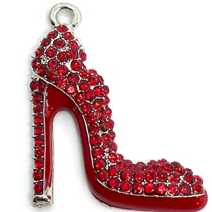 May include: A silver charm in the shape of a red high heel shoe. The shoe is covered in red rhinestones.