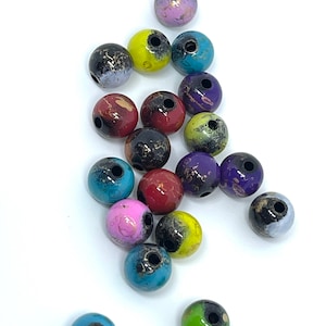 May include: A collection of colorful round beads with black accents and gold flecks. The beads are made of wood and have a glossy finish.