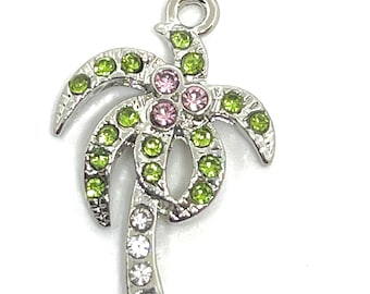 May include: A silver charm in the shape of a palm tree with green and pink rhinestones.