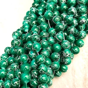 May include: A strand of green glass beads with white swirls. The beads are round and have a glossy finish.