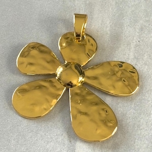 May include: A gold-toned metal flower pendant with a hammered texture. The pendant has five petals and a loop at the top for attaching to a chain.