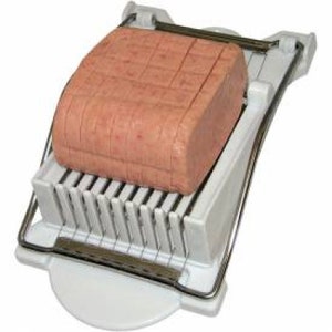 May include: White plastic food slicer with a silver metal frame. A block of pink processed meat is in the slicer.