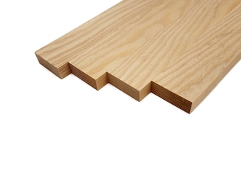 May include: Four pieces of unfinished, light brown wood, stacked on top of each other, with the grain running vertically. The wood is cut into rectangular strips.