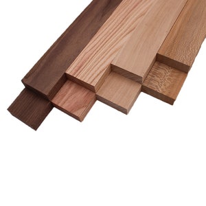 May include: Five different wood samples, arranged in a staggered pattern. The samples are all different colors and grain patterns. The wood samples are all about 1 inch wide and 12 inches long.