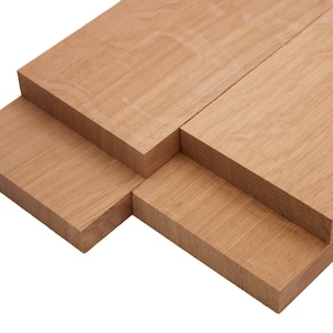 May include: Close-up of several unfinished wooden planks. The planks are a light brown color with visible wood grain. The wood appears to be stacked in a staggered arrangement, showcasing the end grain and side grain.