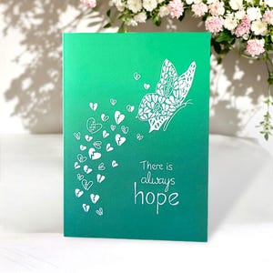 Biglietto di auguri con farfalle di supporto - Immagine in linoleum in verde speranza con le parole "C'è sempre speranza". Per inviare amore e supporto