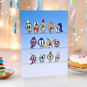 Carte de jeu de mots Bird Day - Design amusant et mignon pour enfants et adultes. Envoyez un sourire avec des oiseaux coiffés d'un chapeau de fête portant les mots « Journée des oiseaux ». Jeu de mots sur les oiseaux