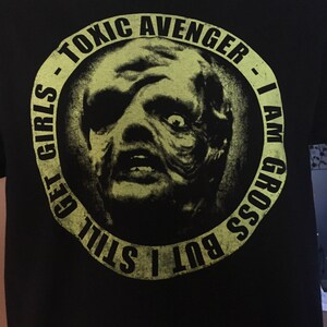 May include: Black t-shirt with a green circle graphic featuring a monster's face and the text "Toxic Avenger - I Am Gross But I Still Get Girls".
