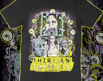 Puede incluir: Una camiseta negra de manga corta con un estampado gráfico de personajes de la película Thirteen Ghosts. El diseño incluye una jaula central, varias figuras y símbolos circulares en tonos amarillos, morados y blancos sobre un fondo oscuro.