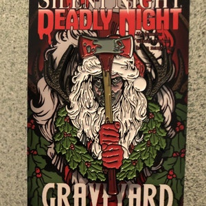 Può includere: Spilla raffigurante un minaccioso Babbo Natale con un'ascia, con il testo "SILENT NIGHT DEADLY NIGHT" in rosso. Il design include una ghirlanda di agrifoglio e le parole "GRAVEYARD CLASSICS.NET". La spilla ha uno sfondo scuro e un tema horror vintage.