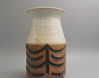 May include: A white ceramic vase with a brown and black geometric design. The vase has a rounded body and a slightly flared opening.