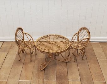 May include: A gold-colored metal patio set with a round table and two chairs. The set is made of woven wire and has a delicate, ornate design.