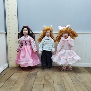 1/12 scale dollhouse miniature girl doll with porcelain hands, feet and head. Fiber hair. Fully poseable doll for miniature scene.
