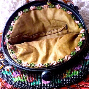May include: A vintage beaded purse with a black base and colorful beads. The purse has a brown fabric lining and a black plastic clasp. The purse has a fringe of beads around the bottom.