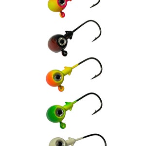 May include: Five jig heads with different colored heads. The heads are yellow, black, orange, green, and white. Each jig head has a black hook.