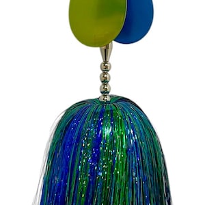 May include: A green and blue fishing lure with a long, fluffy tail. The lure has two round, metallic blades.