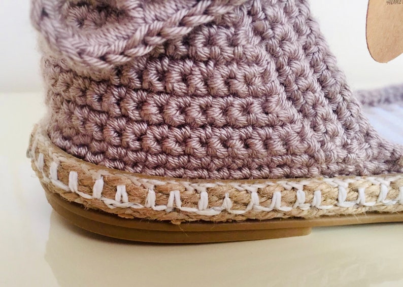 May include: A pair of beige crochet espadrille sandals with a white jute sole.