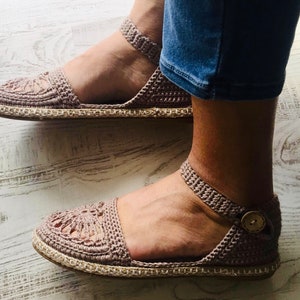 May include: A pair of crocheted sandals with a beige jute sole. The sandals have a delicate, lacy design and are perfect for warm weather.