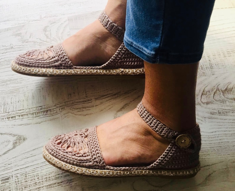 May include: A pair of crocheted sandals with a beige jute sole. The sandals have a delicate, lacy design and are perfect for warm weather.