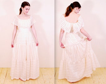 Puede incluir: Un vestido maxi blanco de encaje con un escote de volantes y una falda de capas. El vestido tiene un corpiño ajustado y una falda fluida.