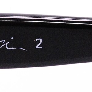 May include: Close-up of the black frame of a pair of eyeglasses with the text "Carlo Zucchi 2 FRAME HONG KONG" printed in white.