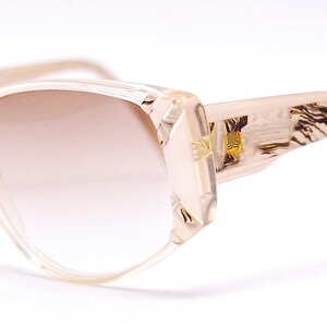 May include: A pair of brown and beige plastic sunglasses with a tortoiseshell pattern on the arms. The lenses are a gradient brown color.