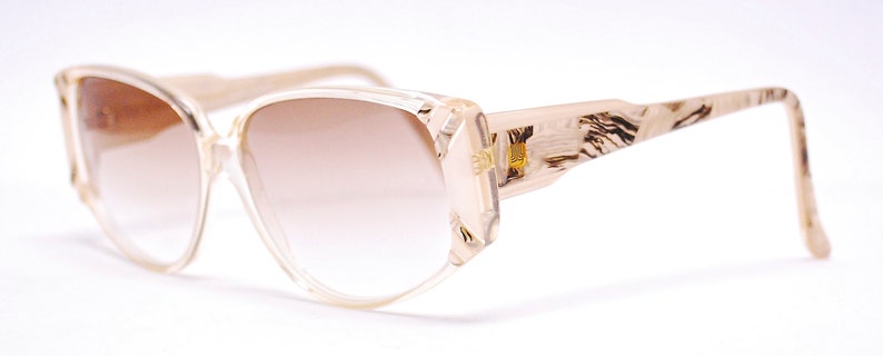 May include: A pair of brown and beige plastic sunglasses with a tortoiseshell pattern on the arms. The lenses are a gradient brown color.