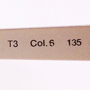 Op de afbeelding: Close-up van een zilverkleurig metalen frame met de tekst "T3 Col. 6 135" erop gedrukt.