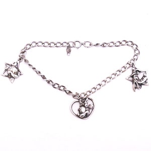 May include: A silver charm bracelet with three charms: a star with a cartoon face, a heart with a cartoon face, and a star with a cartoon face.