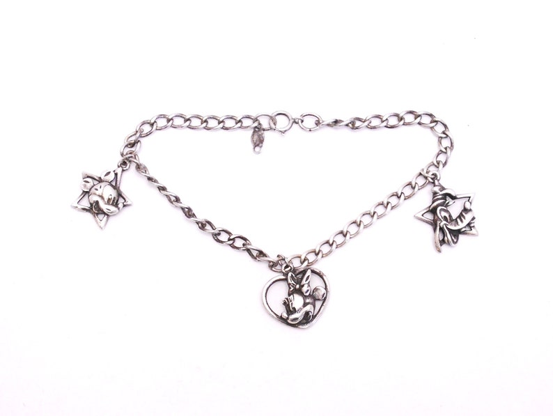 May include: A silver charm bracelet with three charms: a star with a cartoon face, a heart with a cartoon face, and a star with a cartoon face.