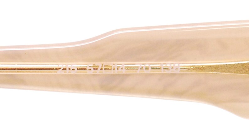 May include: Close-up of the inside of a pair of sunglasses with the text "2165 52 17 140 135" printed on the inside of the arm.
