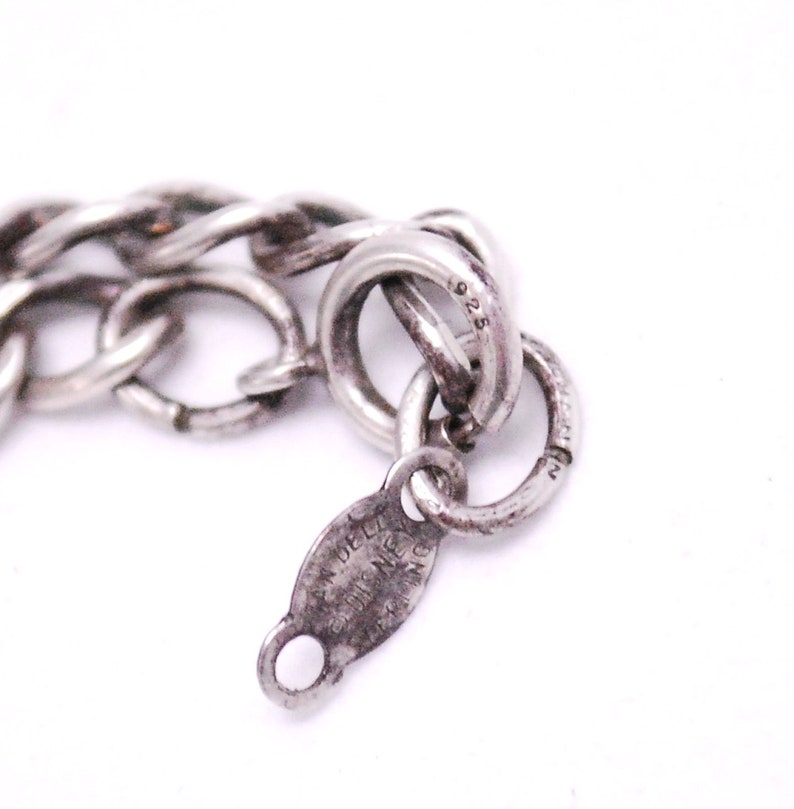 May include: Close-up of a silver chain bracelet with a clasp that reads "925" and "VAN DELL'Y STERLING NEW YORK".
