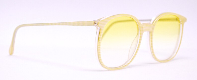 May include: A pair of yellow tinted eyeglasses with a clear plastic frame. The frame has a textured pattern.