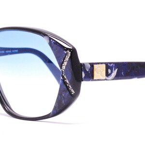 May include: Black and blue patterned eyeglasses with blue tinted lenses. The brand name "Calvin Klein" is printed on the left lens.