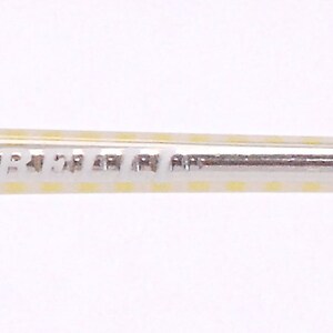 May include: Close-up of a yellow and white striped frame with the text "frame italy" printed on the metal.