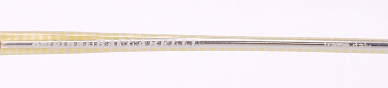 May include: Close-up of a yellow and white striped frame with the text "frame italy" printed on the metal.
