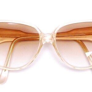 May include: A pair of clear, plastic framed sunglasses with brown gradient lenses. The sunglasses have a cat-eye shape.