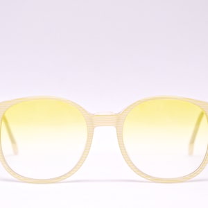 May include: A pair of round, yellow-tinted sunglasses with a white striped frame.
