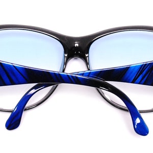 Op de afbeelding: Zwarte en blauwe zonnebril met een blauw-zwart gestreept patroon op de pootjes. De zonnebril heeft een gouden logo op de pootjes dat "D.I.F." zegt.