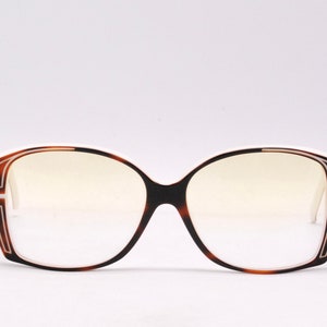 Peut inclure: Une paire de lunettes de vue en &eacute;caille de tortue avec des montures blanches et une bordure blanche autour des verres.