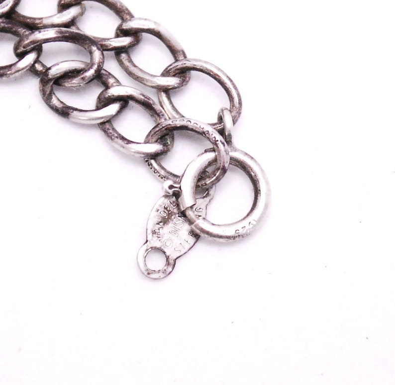 May include: Close-up of a silver chain bracelet with a lobster clasp and a tag that reads "925 ITALY".